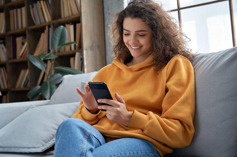a teenage girl looking at her phone and smiling