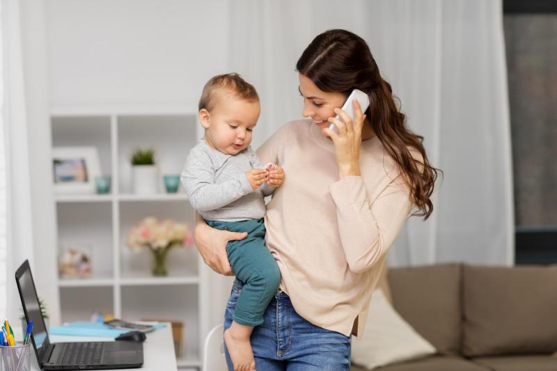 woman on phone call while holding her young child